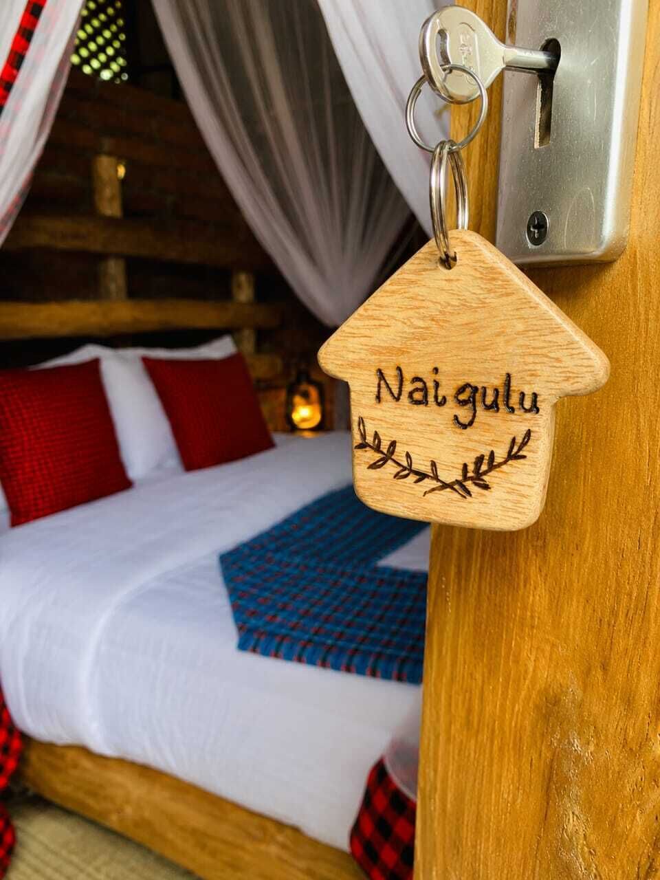 A wooden keychain with 'Nai gulu' engraved on it, hanging on a door lock.
