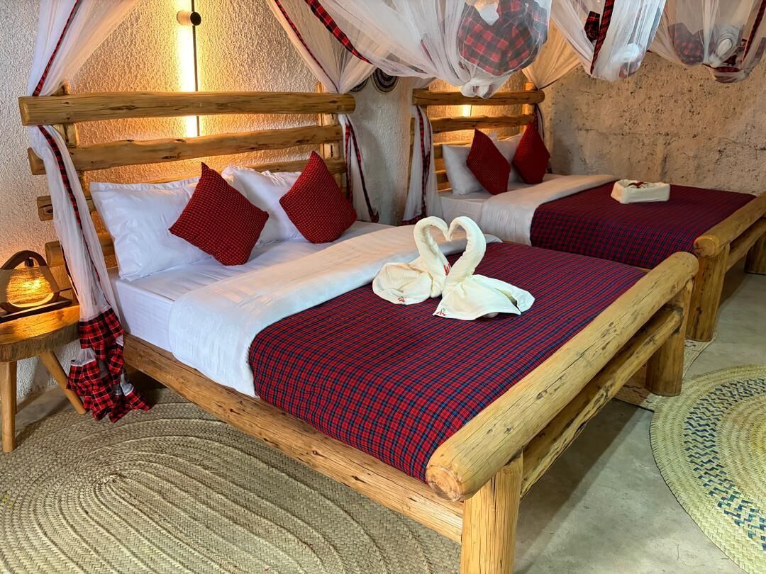 A room with two wooden beds, each with a canopy, and a woven rug on the floor.