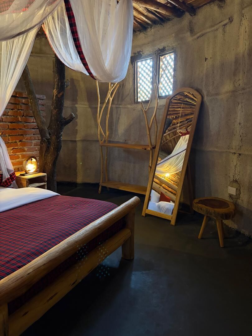 A rustic room with a bed, a hanging chair, and a small table.