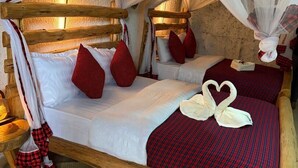Una cama con dosel, ropa de cama roja y blanca, y una alfombra tejida.