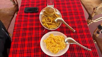 Una mesa dispuesta con mantel a cuadros rojos, platos de comida y una botella de salsa.
