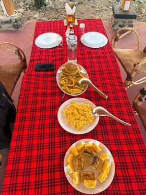 Una mesa dispuesta con mantel a cuadros rojos, platos de comida y una botella de salsa.