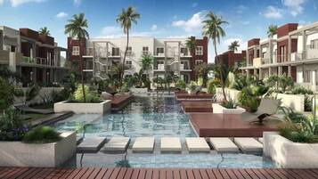 A modern hotel with a central pool, surrounded by lush greenery and palm trees.