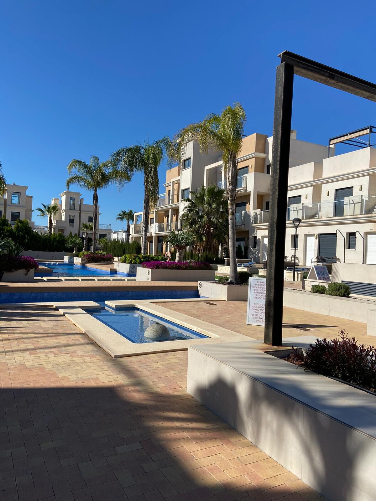 Un resort con varias piscinas, palmeras y edificios modernos.