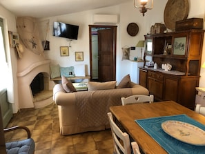 Ein gemütliches Wohnzimmer mit Kamin, einem an der Wand befestigten Fernseher und einem Essbereich mit Holztisch und Stühlen.