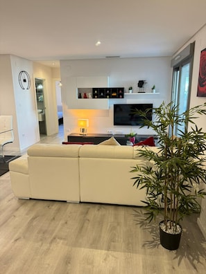 Una sala de estar moderna con un sofá, un televisor y una planta en maceta.