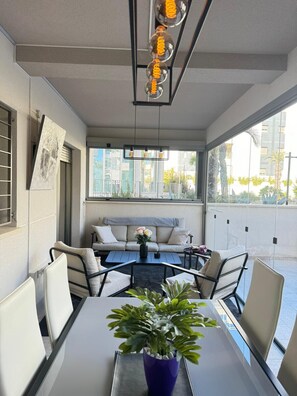 Un área de estar moderna al aire libre con una mesa, sillas, un sofá y una lámpara colgante.