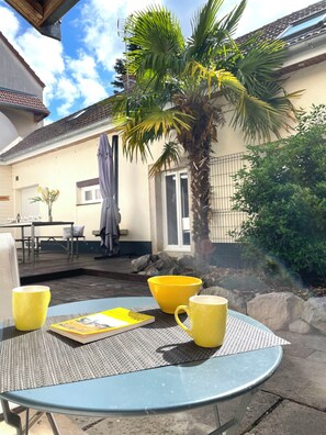 A patio with a table, yellow cups, and a book. - Vrbo Property (Morey-Saint-Denis)
