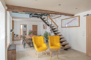 Ein Essbereich mit gelben Stühlen, einem Holztisch und einer Treppe mit hölzerner Geländer.