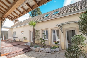 Ein Haus mit Holzterrasse, kleinem Garten und Ziegeldach.