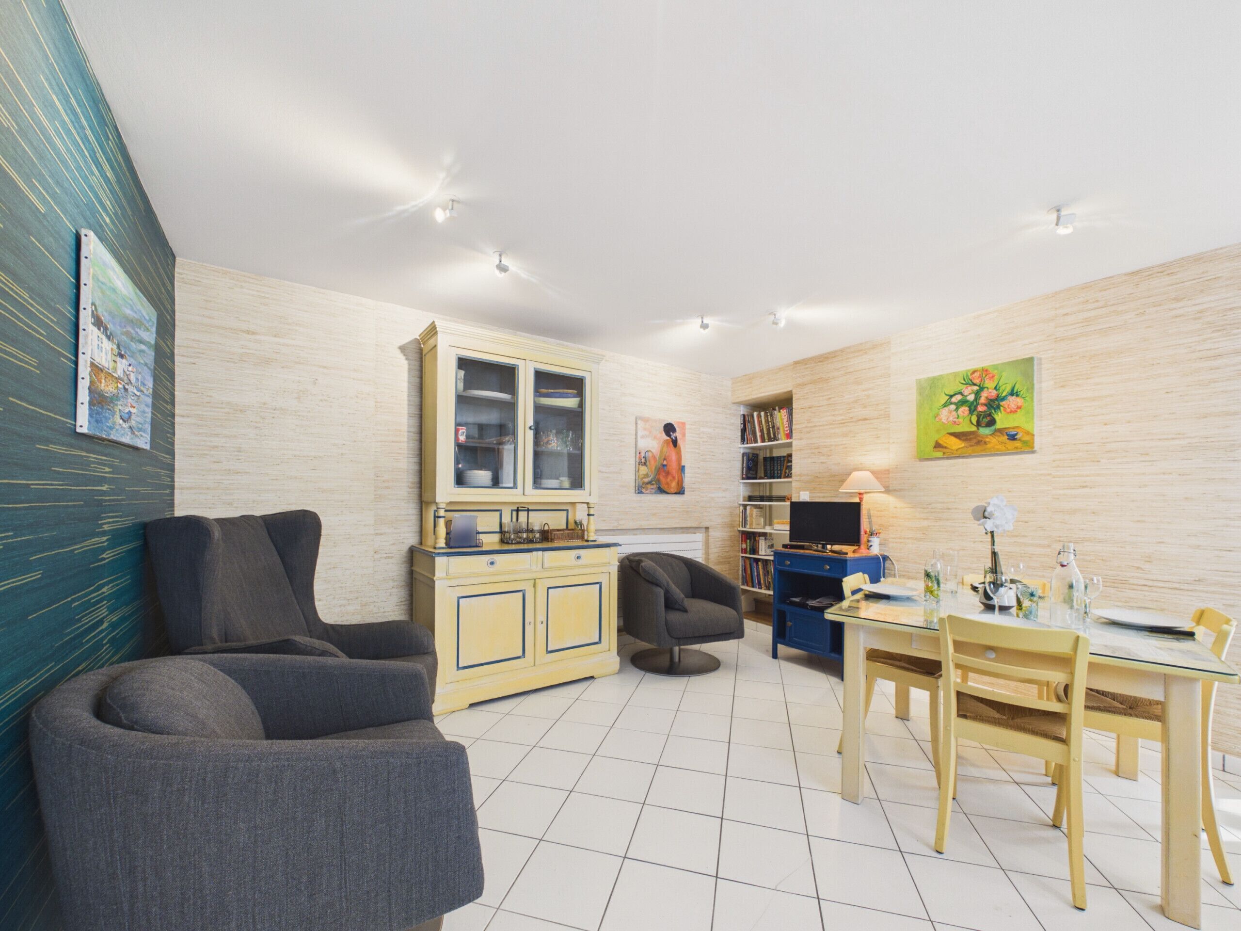 Un salon comprenant un canapé, une table à manger avec des chaises, un meuble et une bibliothèque.