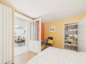 Ein Schlafzimmer mit einem Bett, einem Bücherregal, einem Schreibtisch mit Stuhl und einer Tür zu einem anderen Raum.