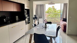 Eine moderne Küche mit Essbereich, Deckenventilator und Blick auf Grünflächen.