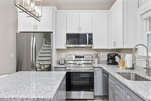 A modern kitchen with white cabinets, stainless steel appliances, granite countertops, and a built-in oven. - Pier View Home Sleeps 10 Pet Friendly (Myrtle Beach)