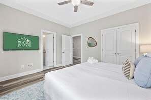 A hotel room with a bed, a ceiling fan, a flat-screen TV, and a sign on the wall. - Pier View Home Sleeps 10 Pet Friendly (Myrtle Beach)
