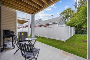 A covered patio area with a grill, chairs, and a table. - Pier View Home Sleeps 10 Pet Friendly (Myrtle Beach)