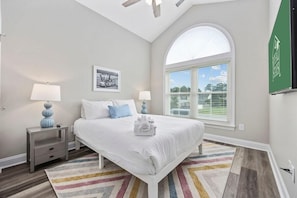 A bedroom with a bed, two bedside tables, a window with blinds, and a ceiling fan. - Pier View Home Sleeps 10 Pet Friendly (Myrtle Beach)
