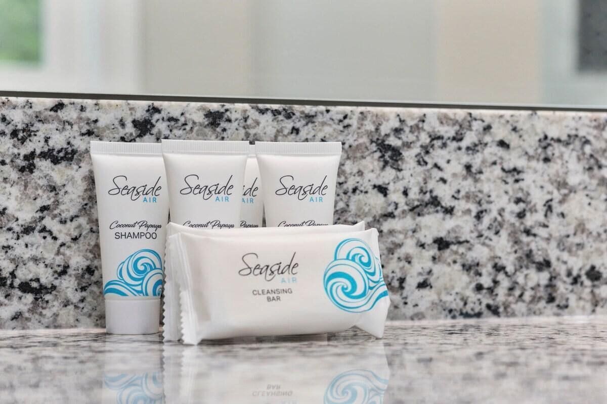 Three tubes of Seaside Air Coconut Papaya Shampoo and a bar of Seaside Air Cleansing Bar on a granite countertop.
