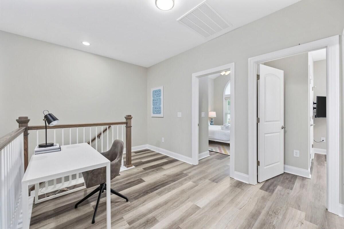 A spacious room with a white desk, a chair, and a staircase.