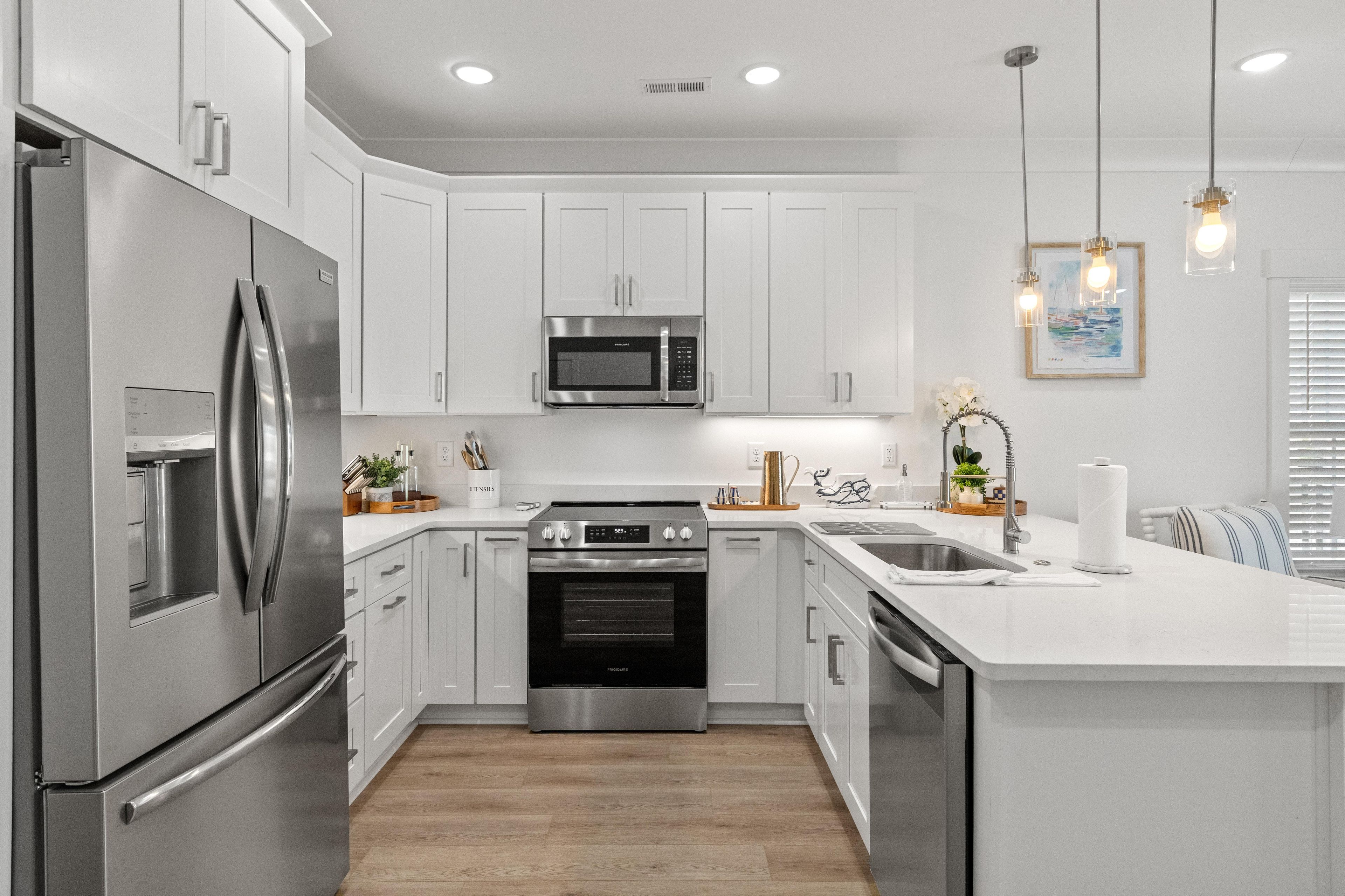 A modern kitchen with stainless steel appliances, white cabinetry, and a central island.