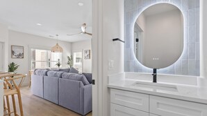 A modern kitchen with a white countertop, a round mirror, and a built-in oven. - Beachwalk Club Steps to Beach Sleeps 16 Pets (Myrtle Beach)
