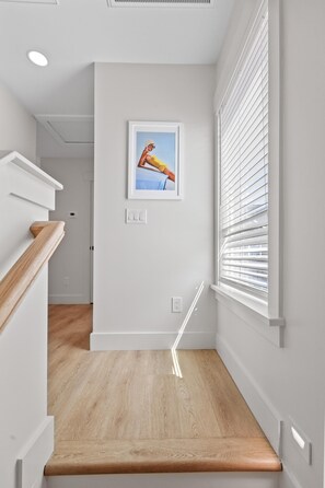 Een modern interieur met een houten trap, witte wanden en een lijst met een afbeelding.