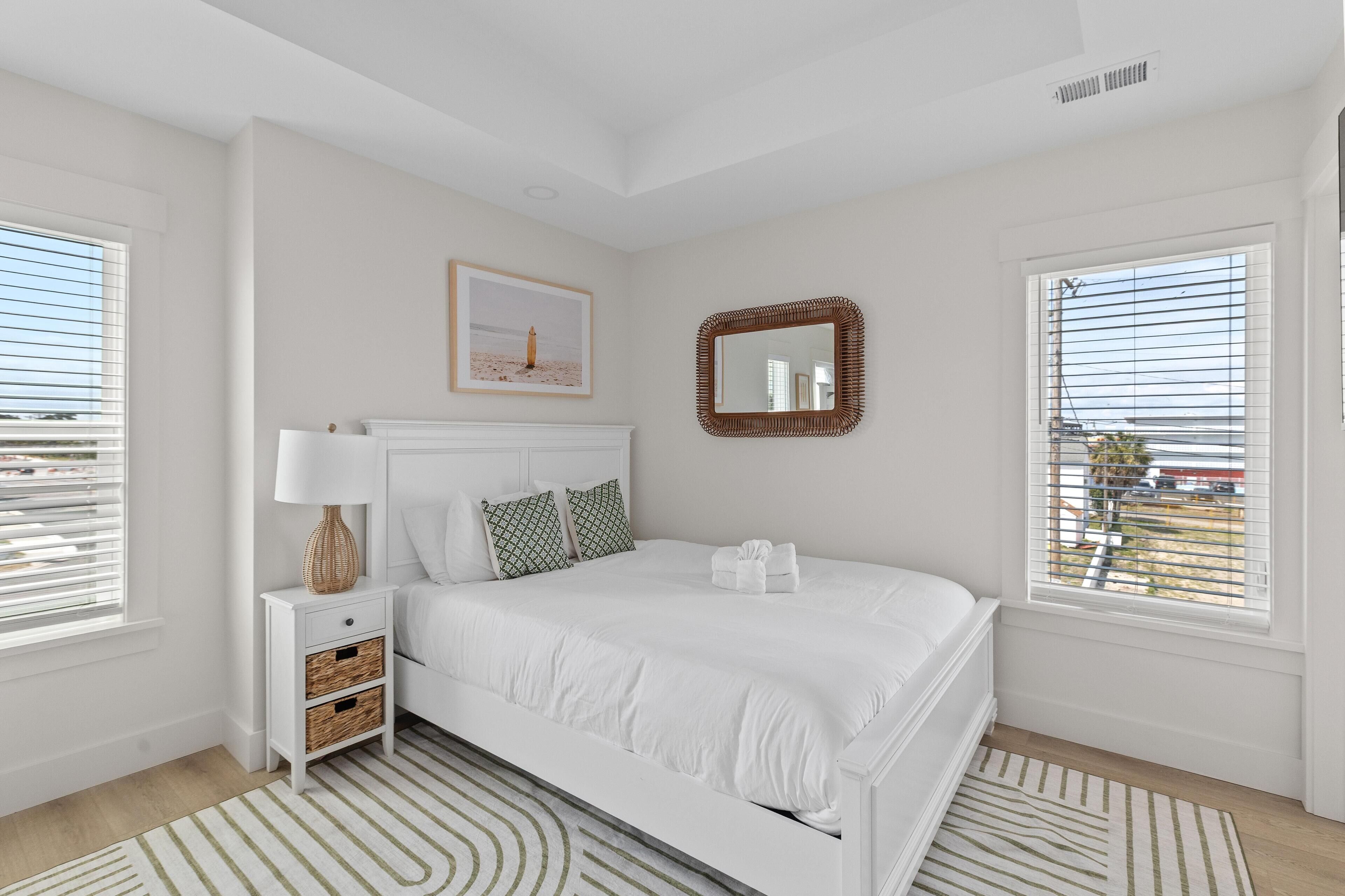 A bedroom with a bed, bedside table, lamp, and a framed picture on the wall.