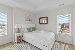 Un dormitorio con cama, mesita de noche, lámpara y un cuadro en la pared.