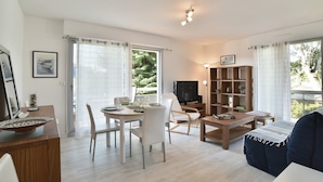 A modern living room with a dining area, a television, and a bookshelf. - Le Balcon d'Émeraude - À moins d’1 km de la plage (Dinard)