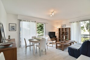 Ein modernes Wohnzimmer mit Essbereich, Fernseher und Bücherregal.