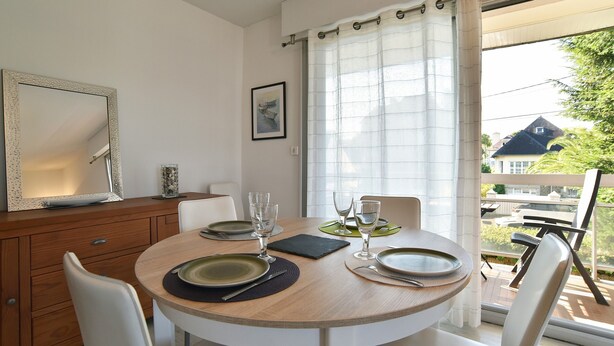A dining area with a round table, chairs, a mirror, and a view of the outside. - Le Balcon d'Émeraude - À moins d’1 km de la plage (Dinard)