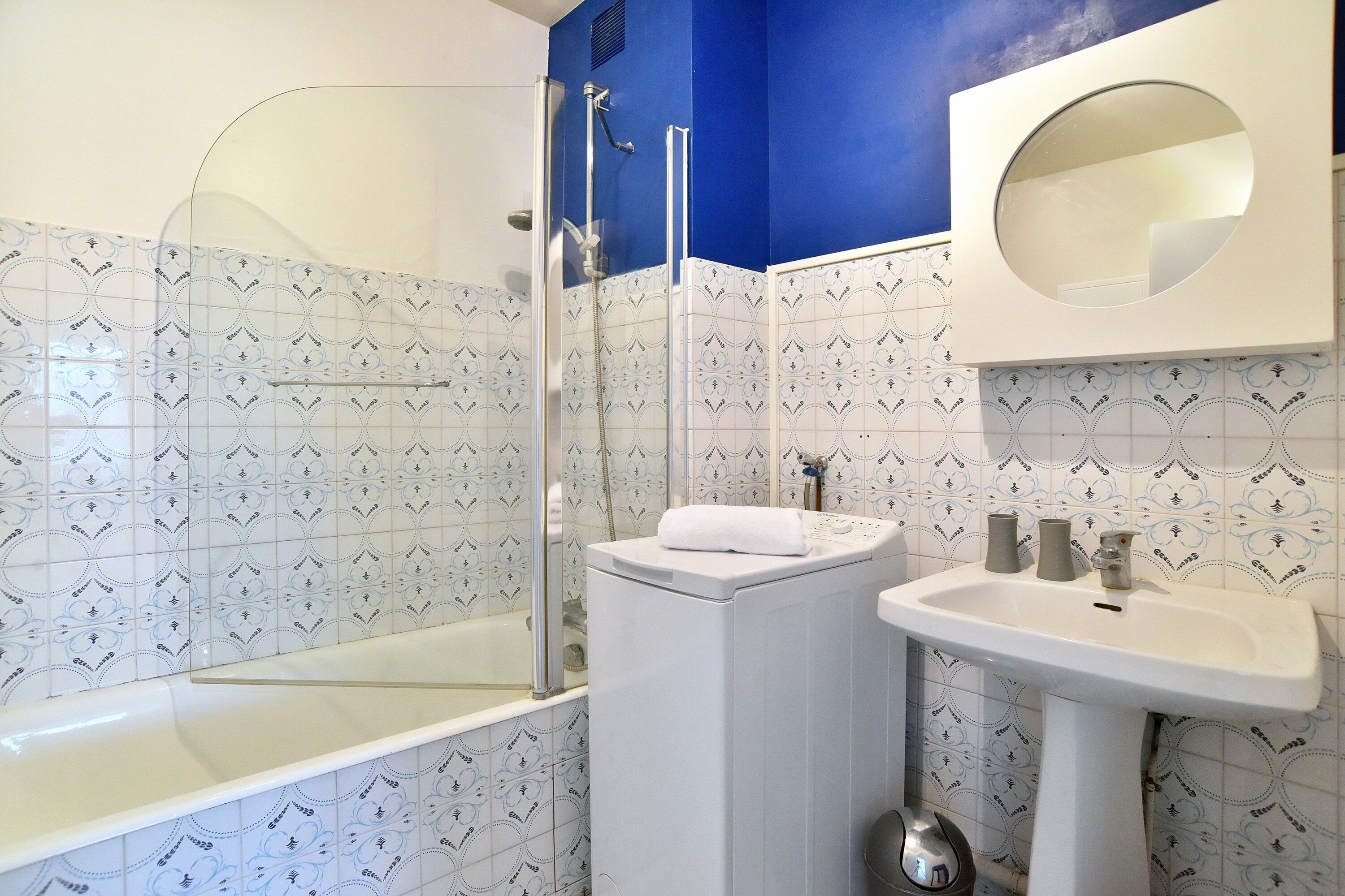 A bathroom with a glass shower enclosure, a white sink, and a mirror above the sink.