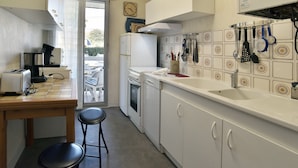 A compact kitchen with a toaster, a sink, and a refrigerator. There is a window with a view of the outside. - Le Balcon d'Émeraude - À moins d’1 km de la plage (Dinard)