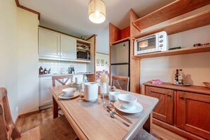 Eine Küche mit Holzausstattung, einem Esstisch gedeckt mit Schüsseln und Tassen, einer Mikrowelle und einem Kühlschrank.
