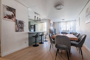 A modern dining area with a wooden table and grey chairs, a kitchen in the background, and artwork on the walls. - Perle de Strasbourg - Bel appt pour 4 avec balcon (Strasbourg)
