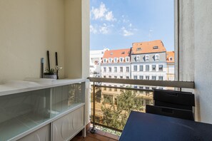 A balcony with a view of buildings, a glass cabinet, and a small table. - Perle de Strasbourg - Bel appt pour 4 avec balcon (Strasbourg)