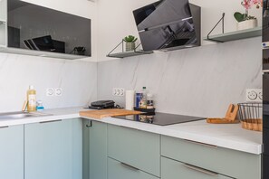 Una cocina moderna con horno empotrado, un lavamanos y una encimera con diversos utensilios de cocina.