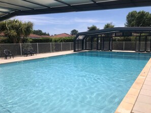 A clear swimming pool with a covered area, surrounded by a fence and chairs. - La Parenthèse Bleue - À 5 min à pied de la plage (Parentis-en-Born)
