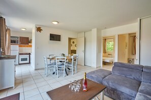 A modern living space with a dining area, kitchen, and a sofa. - La Parenthèse Bleue - À 5 min à pied de la plage (Parentis-en-Born)