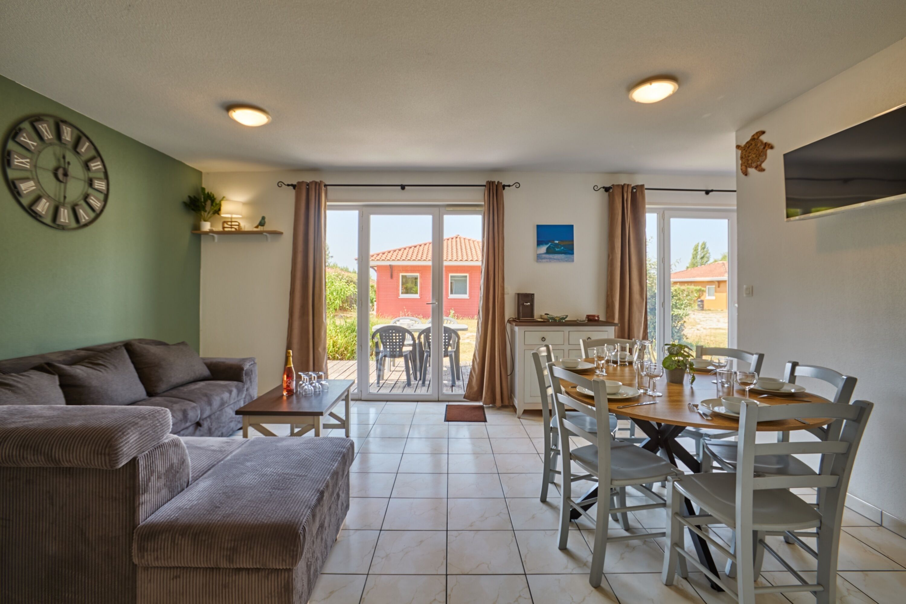 A living room with a sofa, dining table, chairs, and a view through a glass door to an outdoor area.