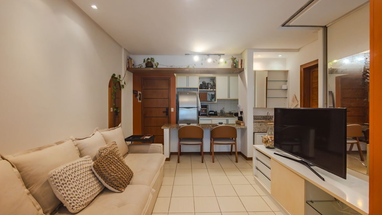 Ein kompakter Wohnbereich mit Sofa, Fernseher, Küchenzeile und Essplatz.