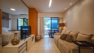 A modern living room with a sofa, a coffee table, a TV, and a dining area with a table and chairs.