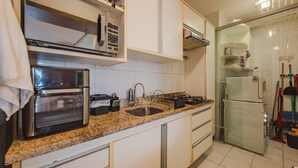 A kitchen with a double oven, a sink, and a refrigerator. - Apto com Garagem a 160m da Praia do Rio Vermelho (Salvador)