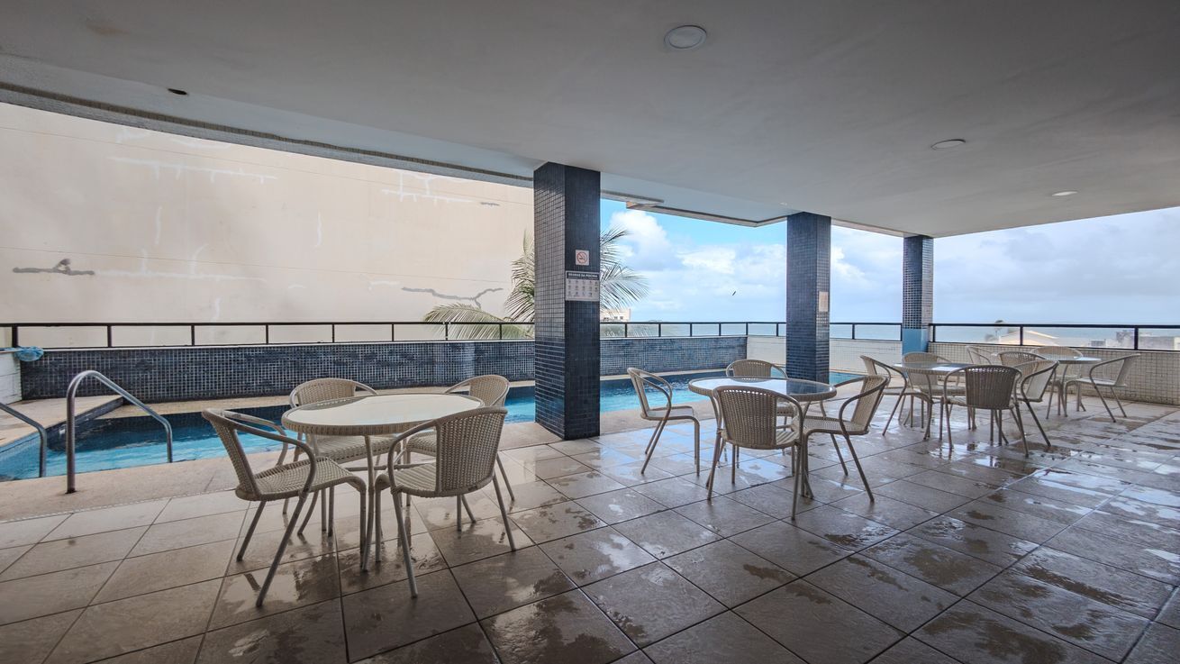 An indoor pool area with tiled flooring, a pool, and multiple seating arrangements.