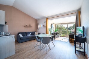 Ein modernes Wohnzimmer mit einem Glastisch, einem grauen Sofa und einem Fernseher auf einem schwarzen Schrank.