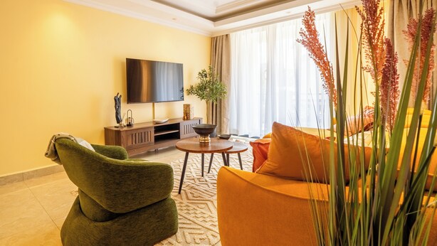 A modern living room with a sofa, a coffee table, and a flat-screen TV mounted on the wall. - Tranquil 2-bedroom apartment in welcoming Nairobi neighborhood (Nairobi)