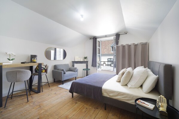 A bedroom with a bed, desk, chairs, and a window.