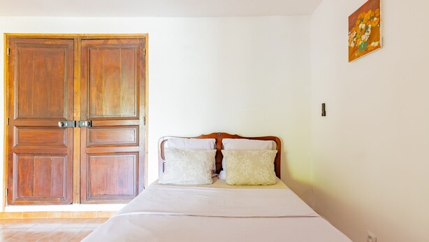 A bedroom with a bed, wooden wardrobe, and a painting on the wall. - Le Clos des Plaisirs - Studio avec jacuzzi privé (Carcassonne)