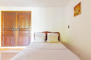 Une chambre à coucher avec un lit, une armoire en bois et un tableau accroché au mur.