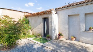 A building with a tiled roof, a door, and potted plants. - Le Clos des Plaisirs - Studio avec jacuzzi privé (Carcassonne)